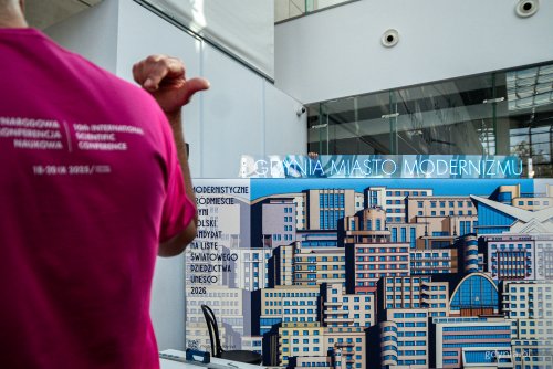 Centrum konferencyjne PPNT Gdynia, ścianka z modernistycznymi budynkami, neonowy niebieski napis 