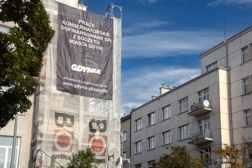 Gdynia, Śródmieście, widoczne fragmenty modernistycznych elewacji, na jednej z nich rusztowania i baner informujący o miejskiej dotacji
