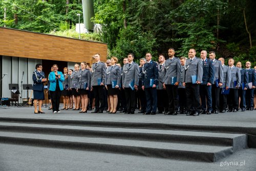 Scena Opery Leśnej w Sopocie, stoi w szeregu duża grupa policjantów w mundurach galowych, z lewej bije brawo prezydent Aleksandra Kosiorek