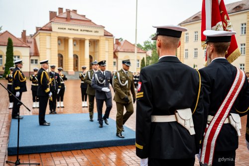 Plac na obiektach Akademii Marynarki Wojennej, marynarze w mundurach, grupa oficerów maszeruje po awanse