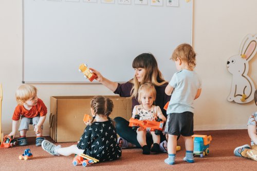 Dzieci w sali z opiekunką i zabawkami