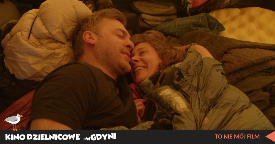 Kadr  filmu „To nie mój film”. Uśmiechnięta para leży przytulona w namiocie.