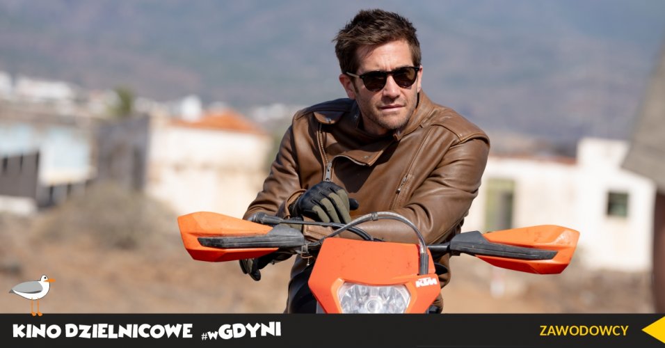 Kadr z filmu "Zawodowcy". Aktor w przeciwsłonecznych okularach siedzi na motocyklu.