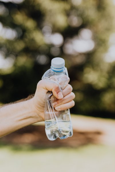 Wyciągnięta ręka ściskająca plastikową butelkę