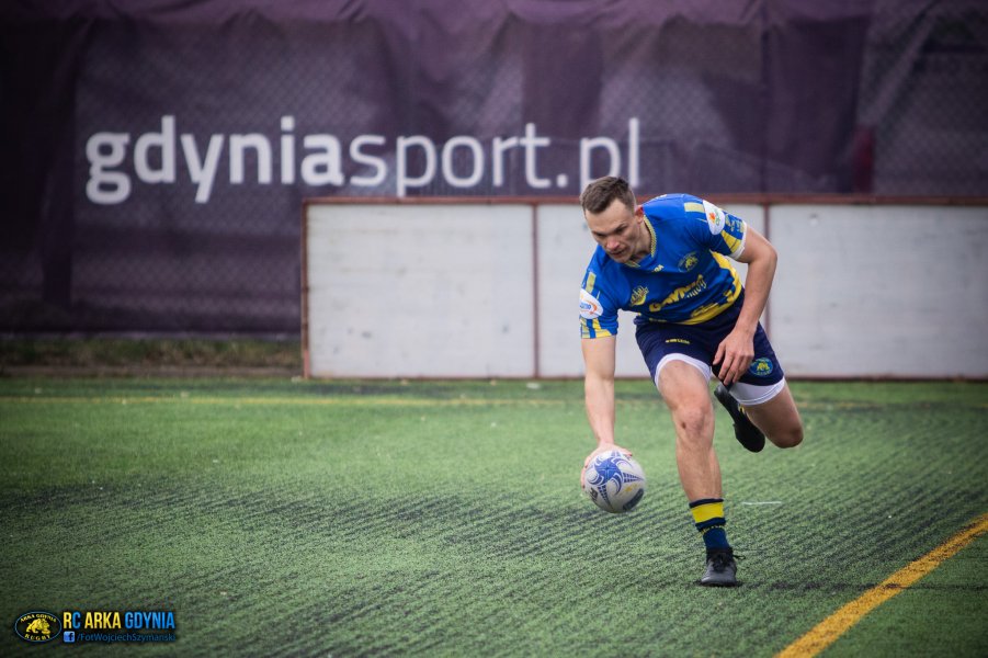 Gracz rugby podnosi piłkę z boiska podczas gry.