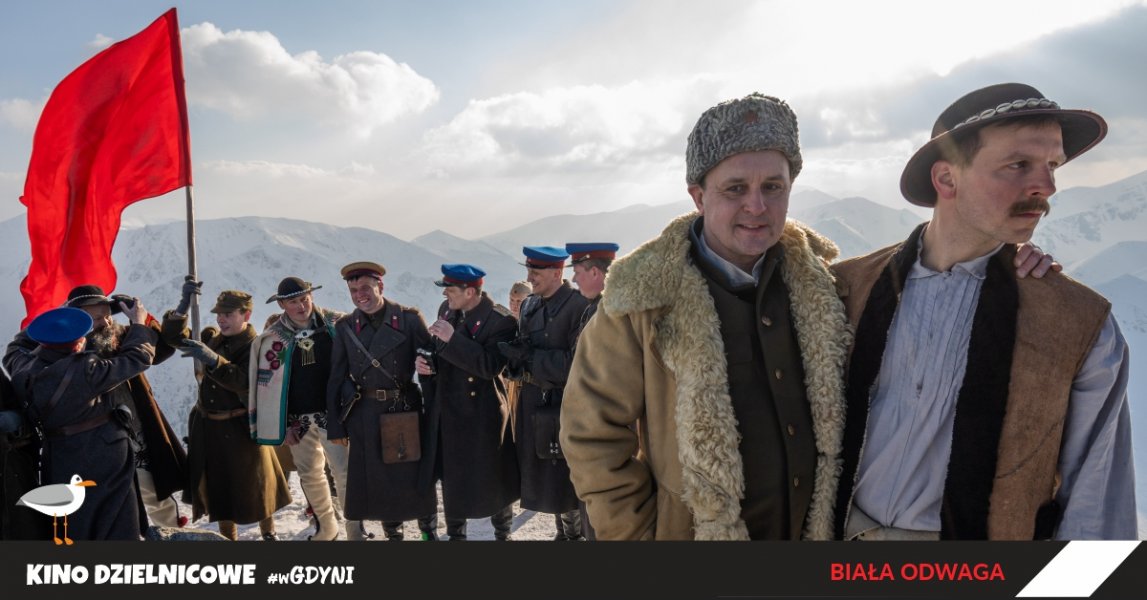 Kadr z filmu Biała odwaga, bohaterowie filmu na tle gór z czerwoną flagą.