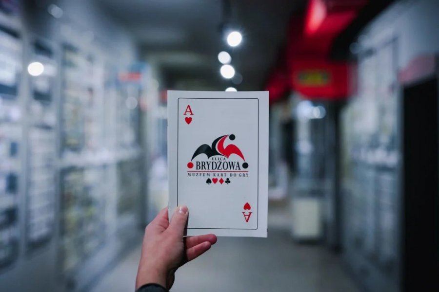 Logo Muzeum Kart w Gdyni trzymane w formie karty do gry