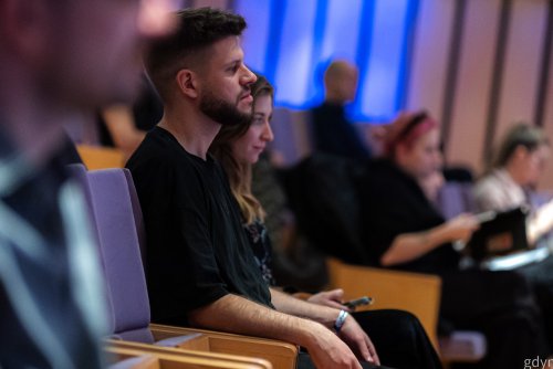 Sala konferencyjna w PPNT Gdynia, mężczyzna i kobieta siedzą na widowni, w tle inni ludzie