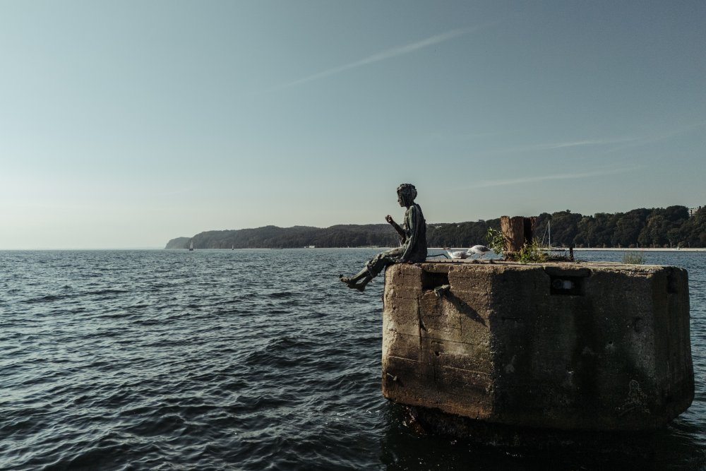 Rzeźba przedstawiająca chłopca dyrygującego falami umieszczona na morzu, na dalbie