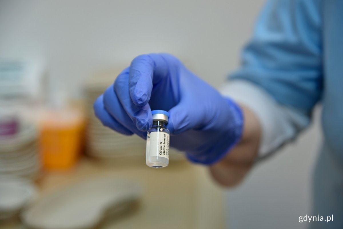 Fiolka ze szczepionką trzymana w dłoni.