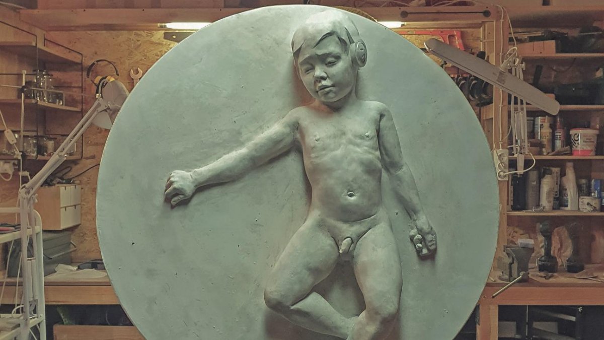 Rzeźba przedstawiająca małego, nagiego chłopca leżącego na plecach na kamiennym kręgu. Wykonał ją gdyński artysta Tewu. Zdjęcie pochodzi z jego prywatnego archiwum