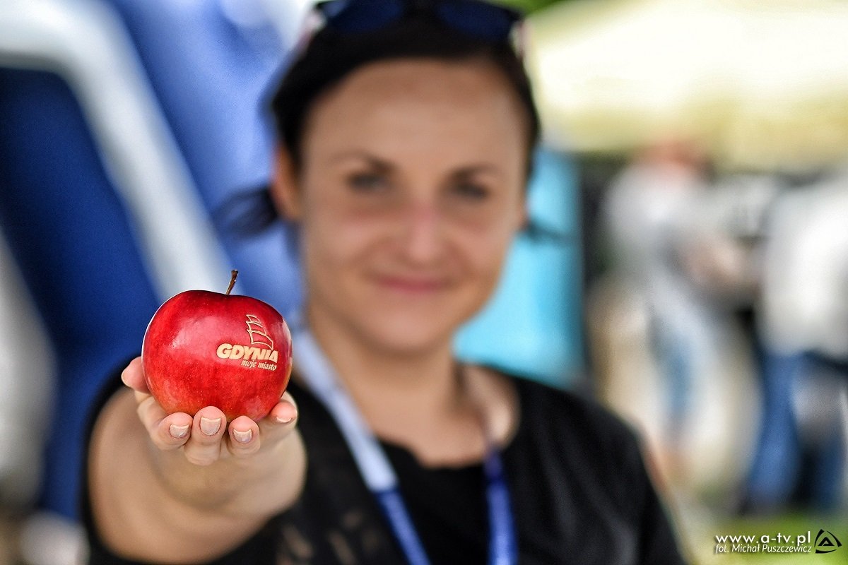 Kobieta trzymająca czerwone jabłko z napisem Gdynia