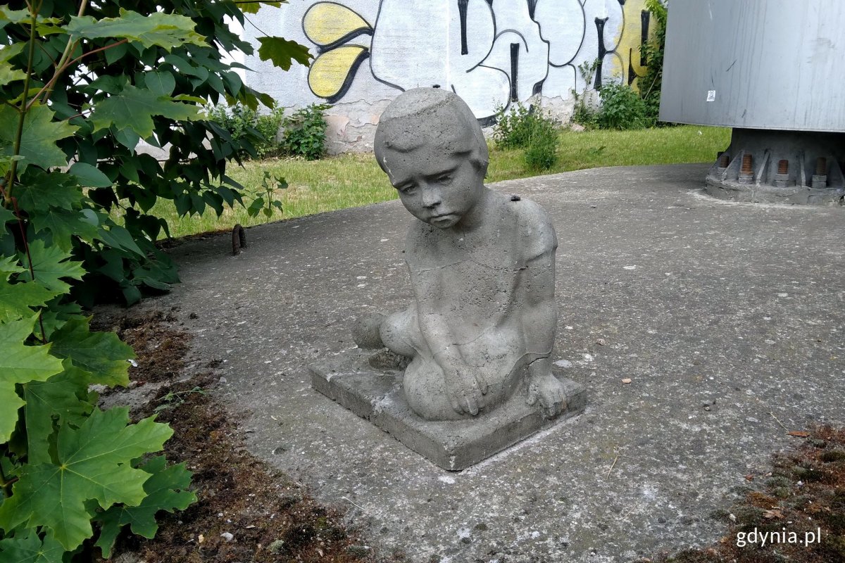 Rzeźba gdyńskiego artysty Tewu - Dziewczynka z ul. Abrahama, która znajduje się za płotem obok sklepu 