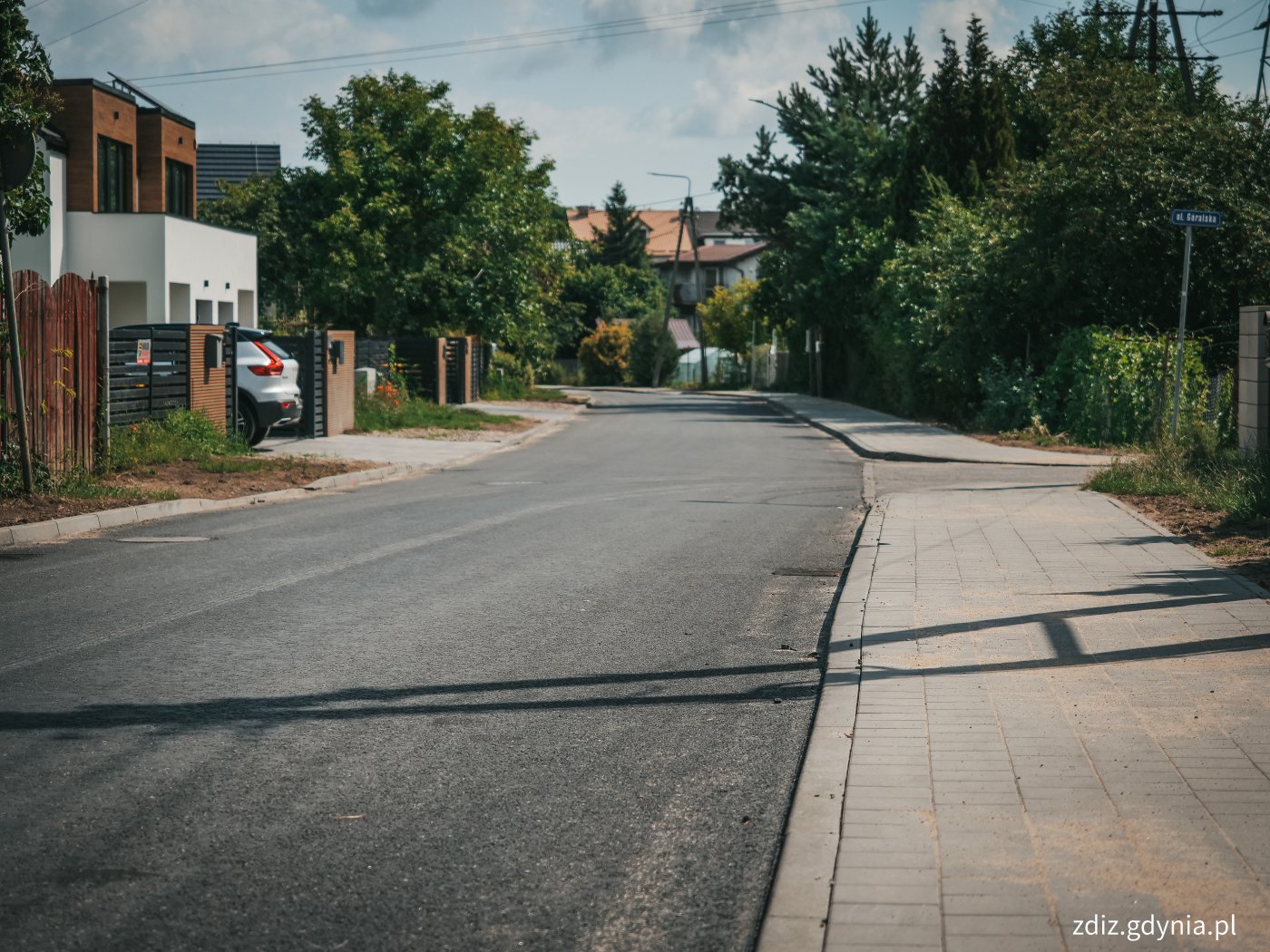 wyremontowana nawierzchnia oraz chodniki, w tle zieleń i budynki