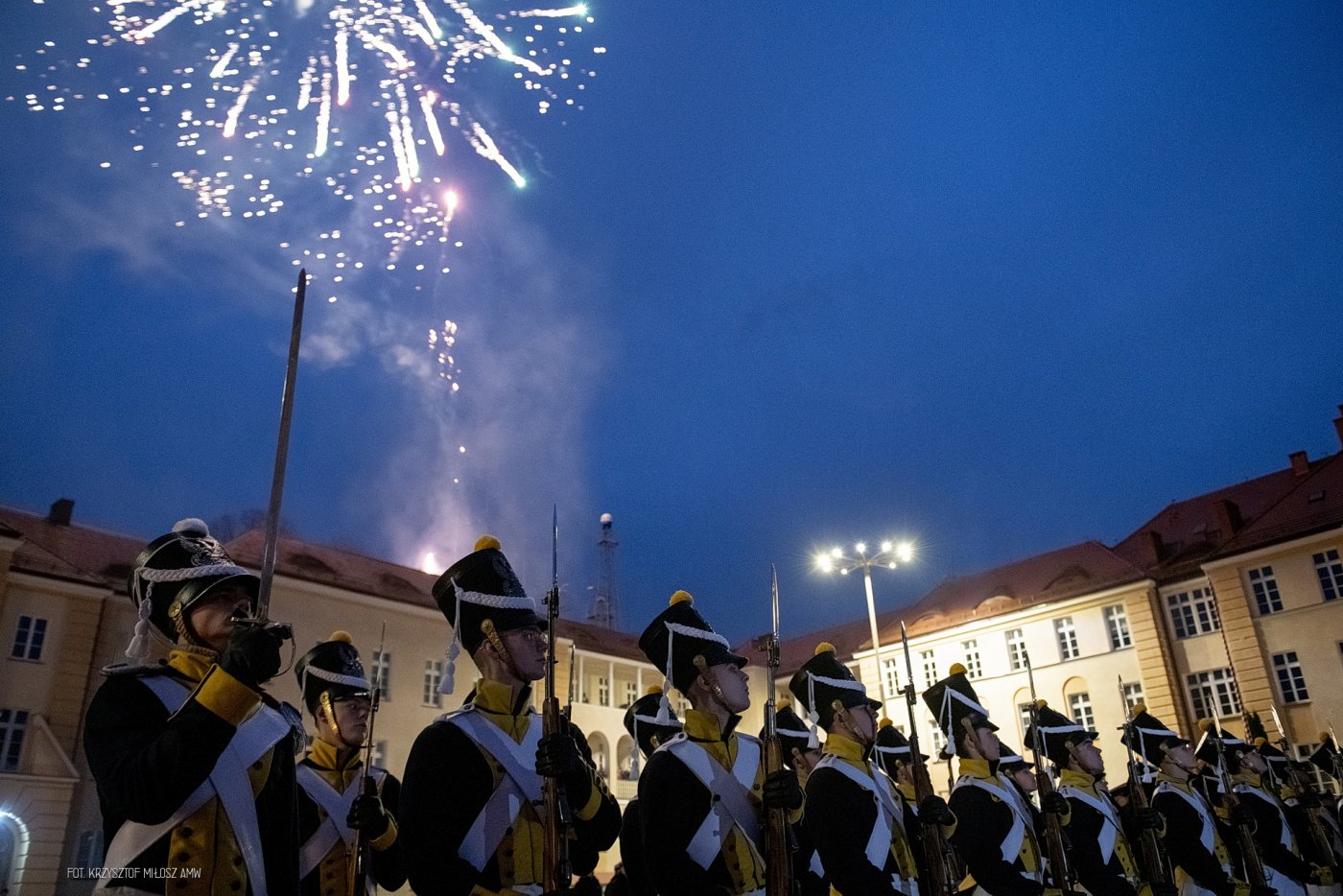 na zdjęciu ludzie w mundurach, w górze fajerwerki