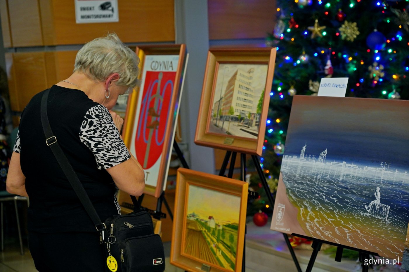 Jedna z uczestniczek prewernisażu wystawy „100 obrazów na 100-lecie Gdyni” oglądająca prace gdyńskich artystów (fot. Magdalena Czernek)