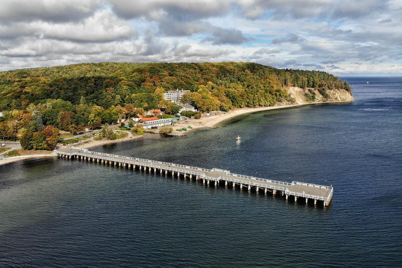 Zdjęcie lotnicze molo w Orłowie, w tle miasto Gdynia i fragment lasu