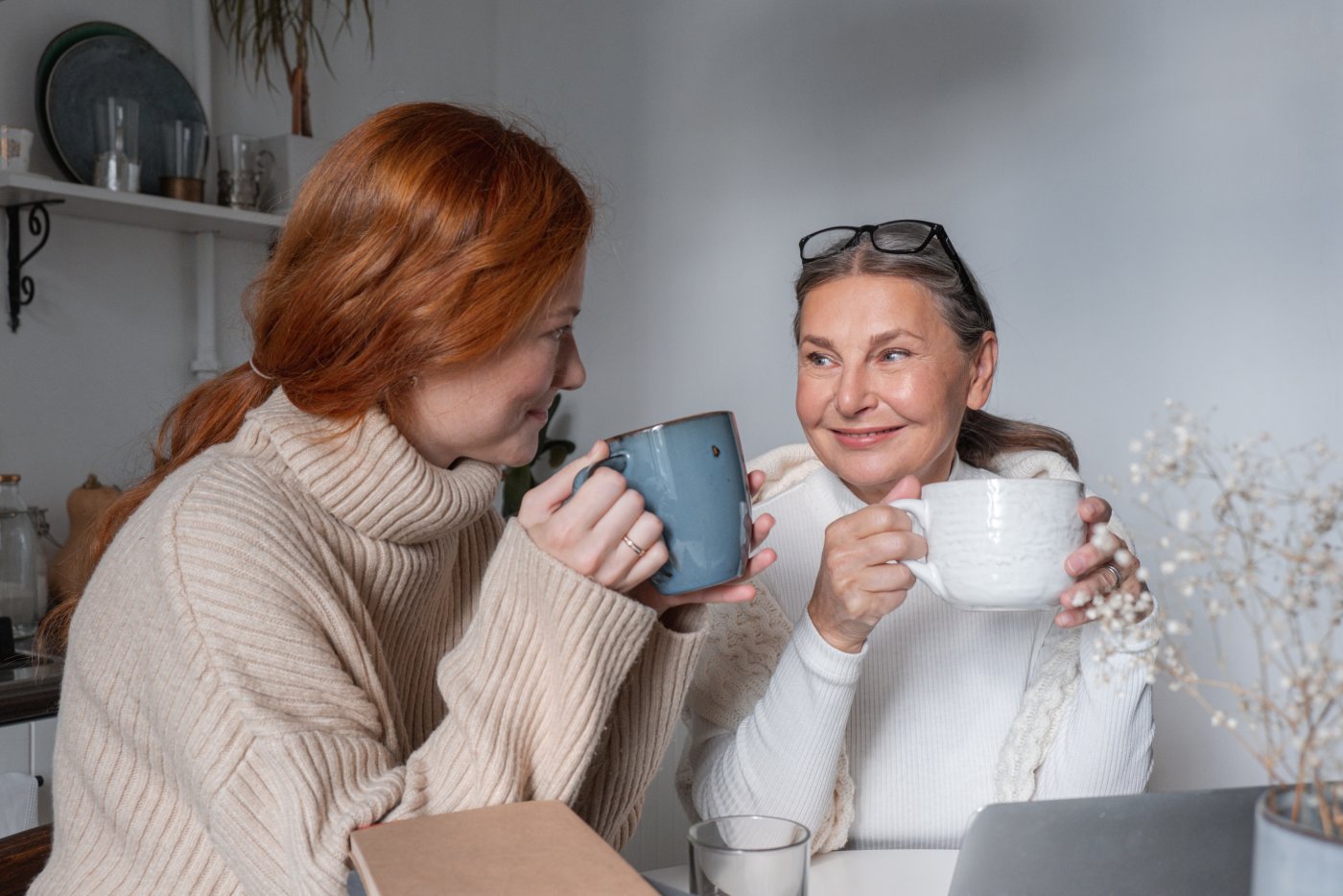 Dwie kobiety, mama z córką, siedzą przy stole i piją kawę.