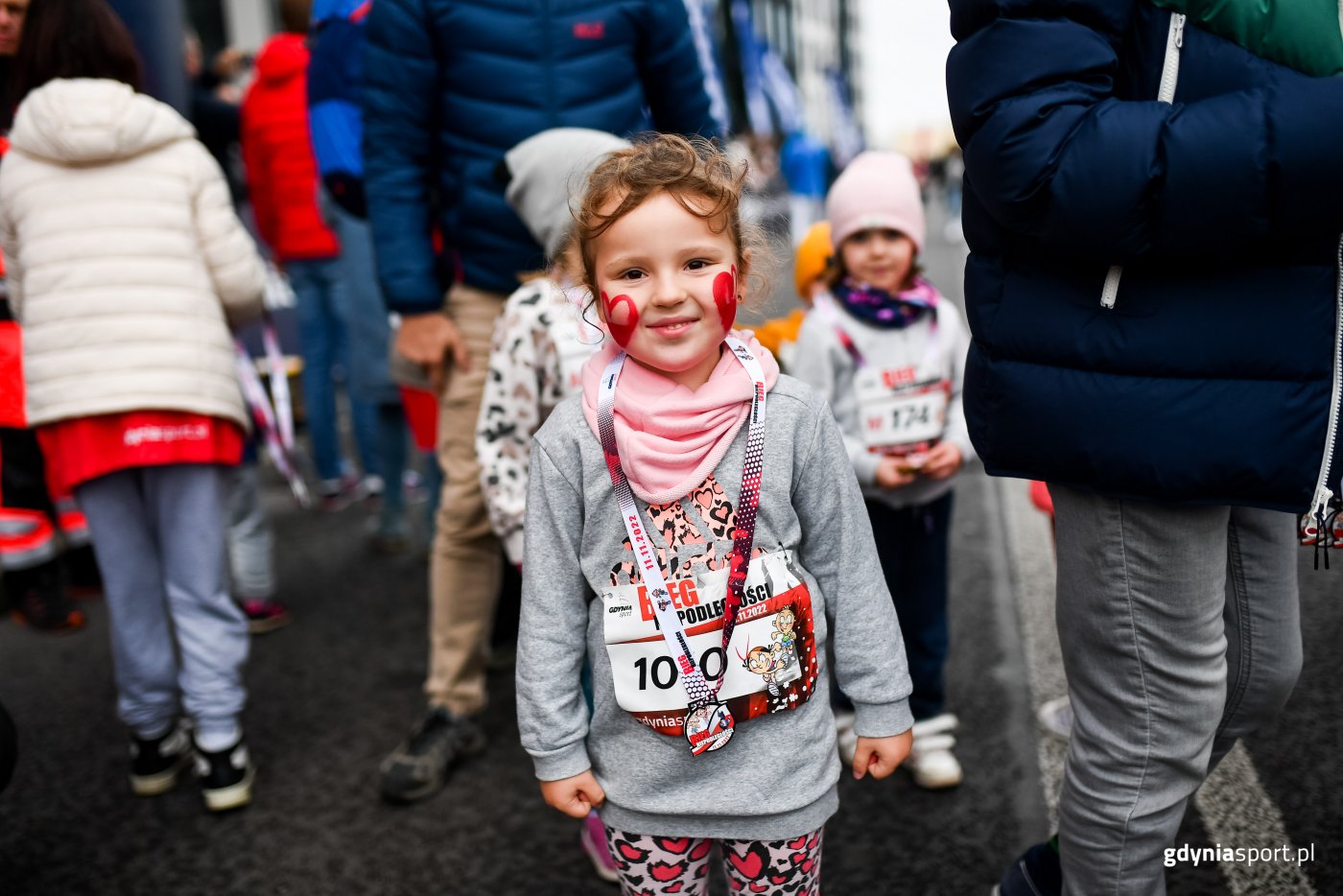 Uśmiechnięta dziewczynka z medalem na mecie Gdyńskiego Biegu Niepodległości (fot. gdyniasport.pl)