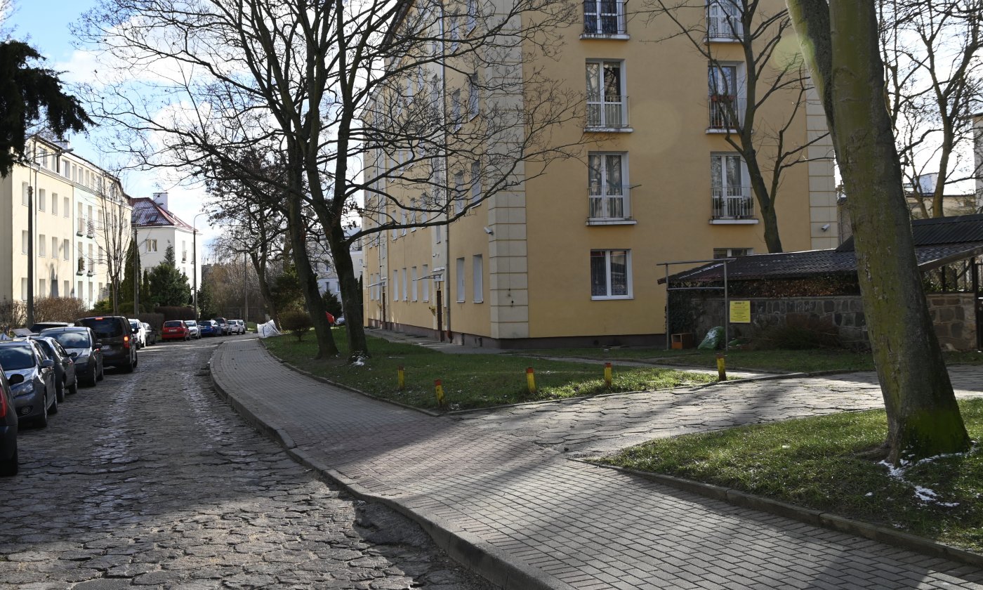 Ulica Augustyna Necla w Gdyni - widok na blok mieszkalny, chodnik, jezdnię oraz drzewa