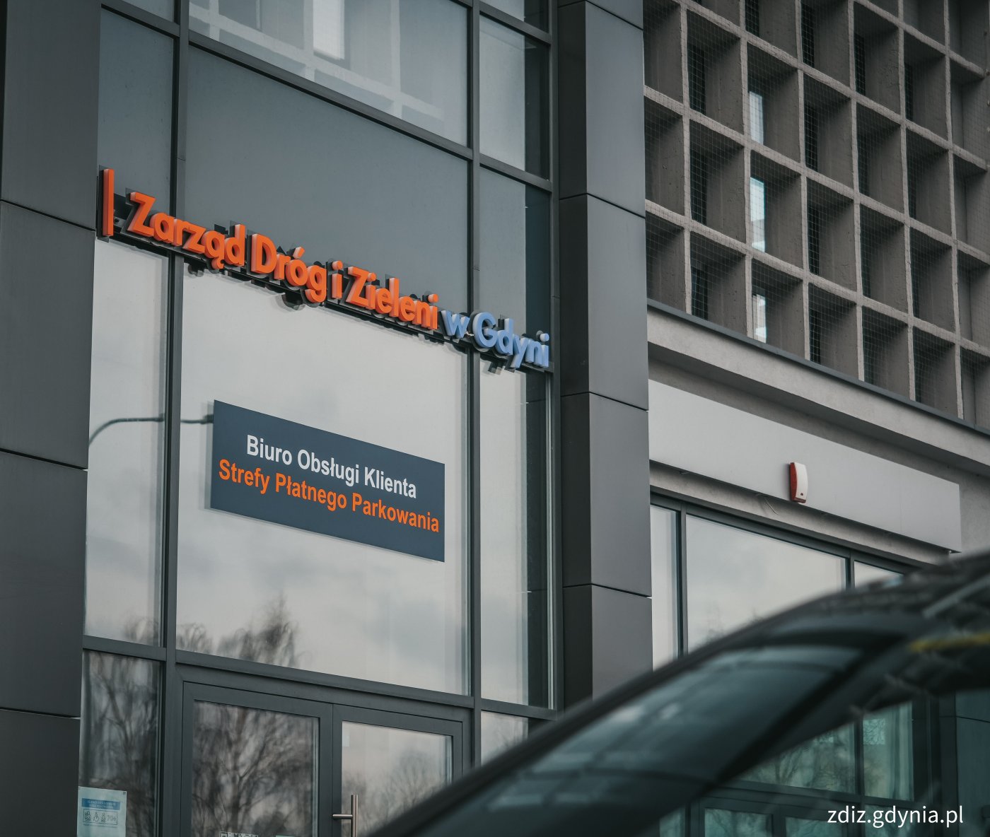 widoczny budynek z napisem Zarząd Dróg i Zieleni w Gdyni Biuro Obsługi Klienta Strefy Płatnego Parkowania