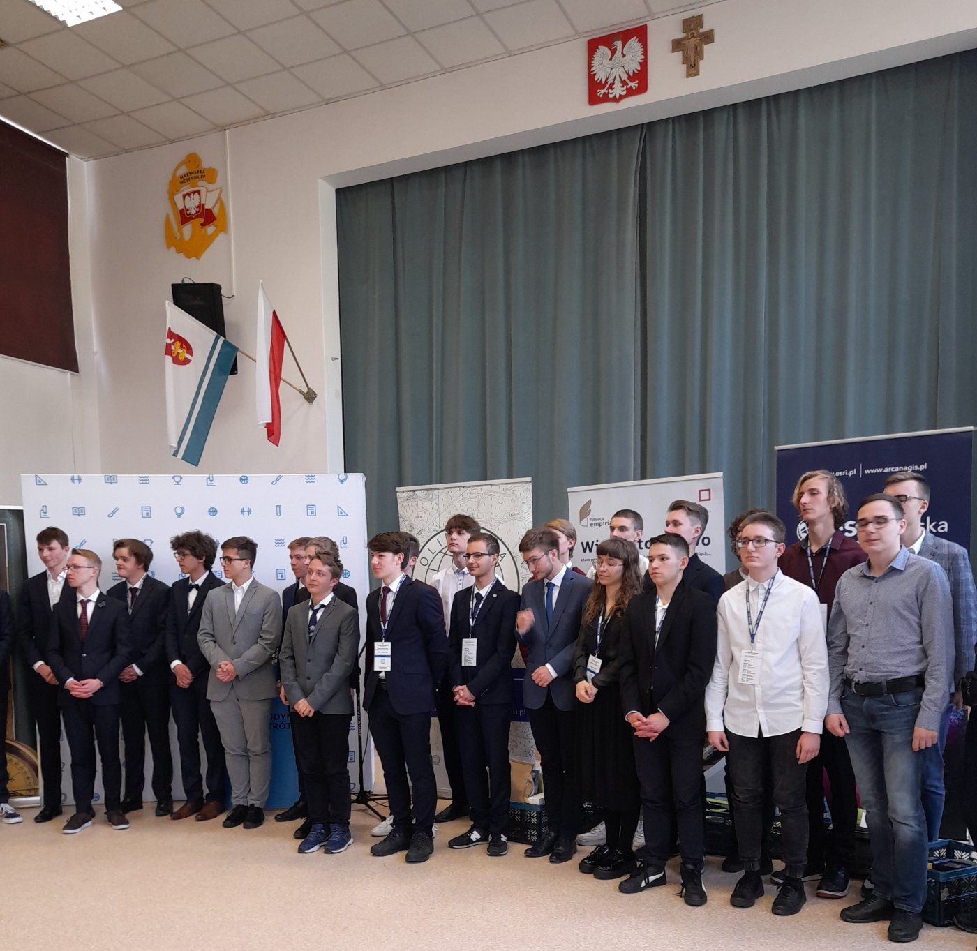 Na zdjęciu grupa 25 osób w auli III LO, w tle niebieskie kotary, flaga Gdyni
