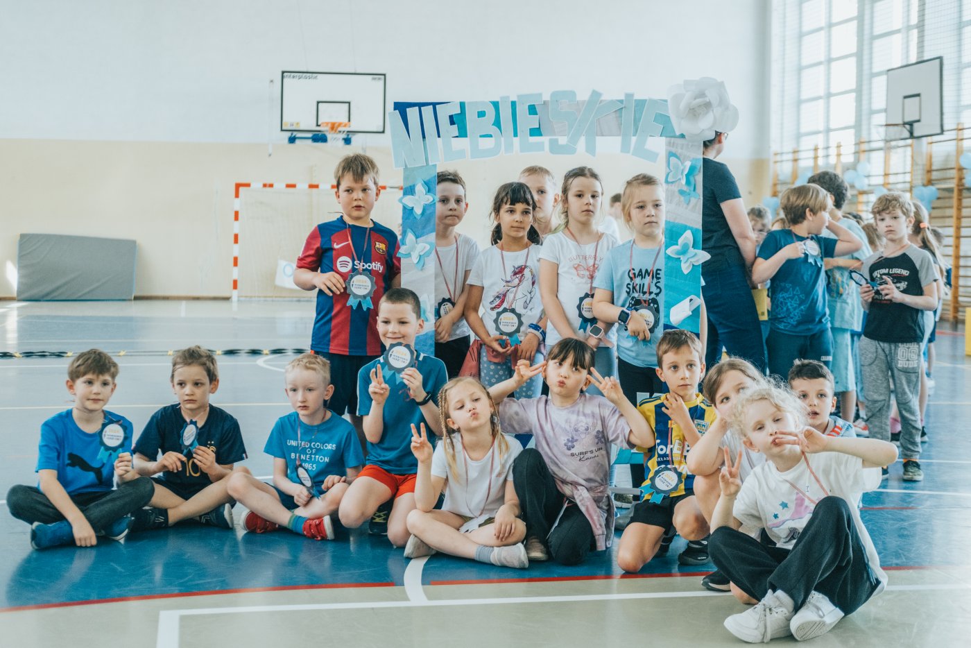 Dzieci w sali gimnastycznej w niebieskich strojach