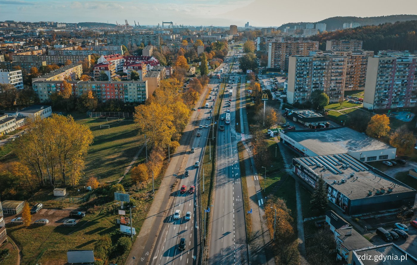 widok z góry na ulicę, widoczny buspas, jezdnie, ruch uliczny. w Tle roślinność i budynki