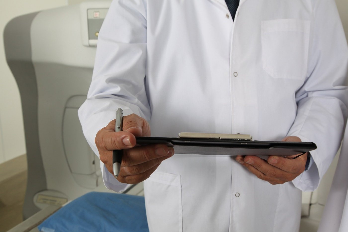 Zdj. ilustracyjne: lekarz w białym kitlu trzyma w rękach notatnik i długopis. Fot. ze strony www.pixabay.com