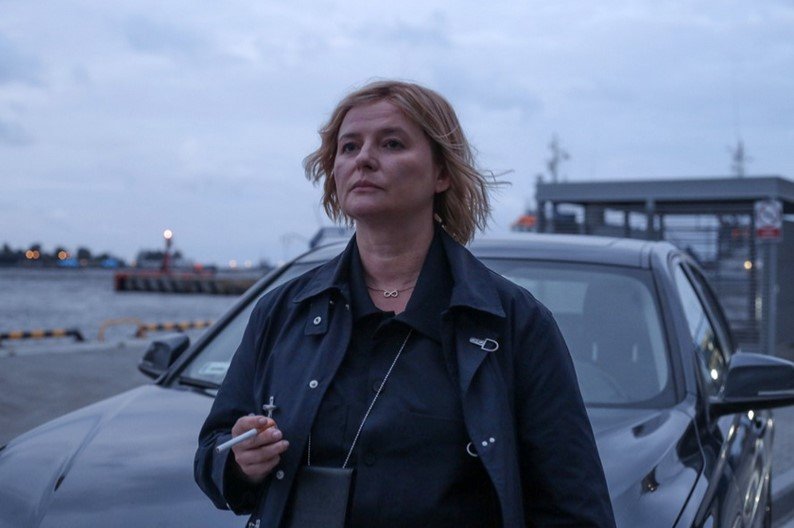 na zdjęciu 40-letnia kobieta stoi przy samochodzie w pochmurny dzień