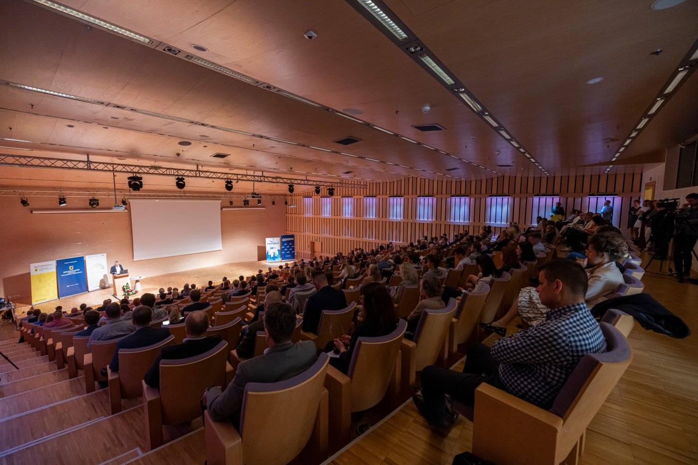 Sala konferencyjna w PPNT Gdynia. Widownia pełna ludzi, na scenie przemawia prelegent.