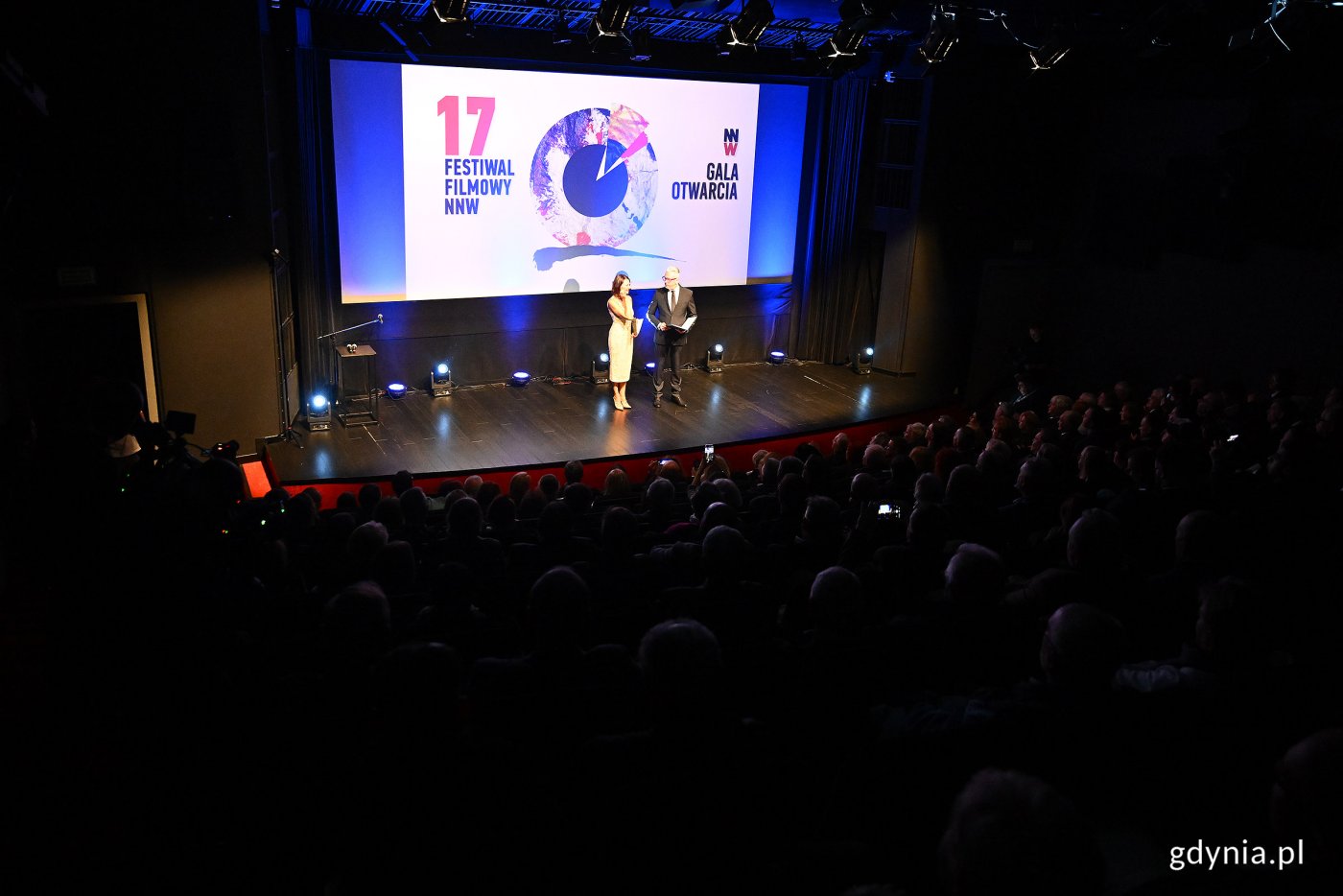 Sala Warszawa w GCF-ie, pełna widownia, prowadzący na scenie, na ekranie logotyp Festiwalu NNW