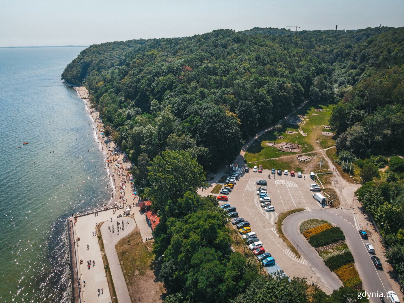 na zdjęciu strzeżone kąpielisko Redłowo, Polanka Redłowska, lato, widoczny tłum turystów na plaży, zieleń, las, bulwar