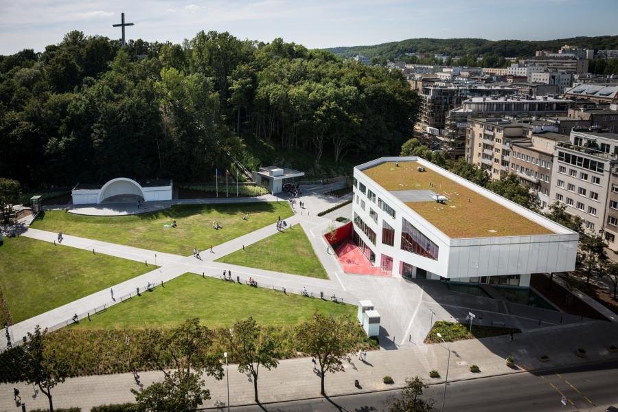 Plac Grunwaldzki widziany z lotu ptaka. Po prawej stronie budynek GCF. Po środku sam plac z krzyżującymi się ścieżkami spacerowymi. W drugim planie Muszla a powyżej drzewa Kamiennej Góry, na szczycie którym widoczny krzyż z Kamiennej Góry.