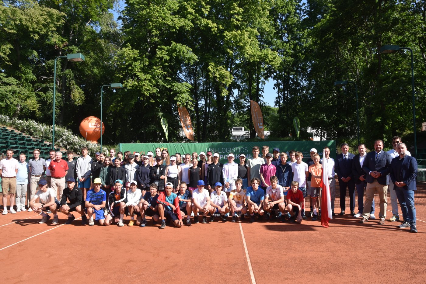 Grupa dzieci i oficjeli podczas uroczystego otwarcia Mistrzostw Polski Młodzików w tenisie. Zdjęcie grupowe.