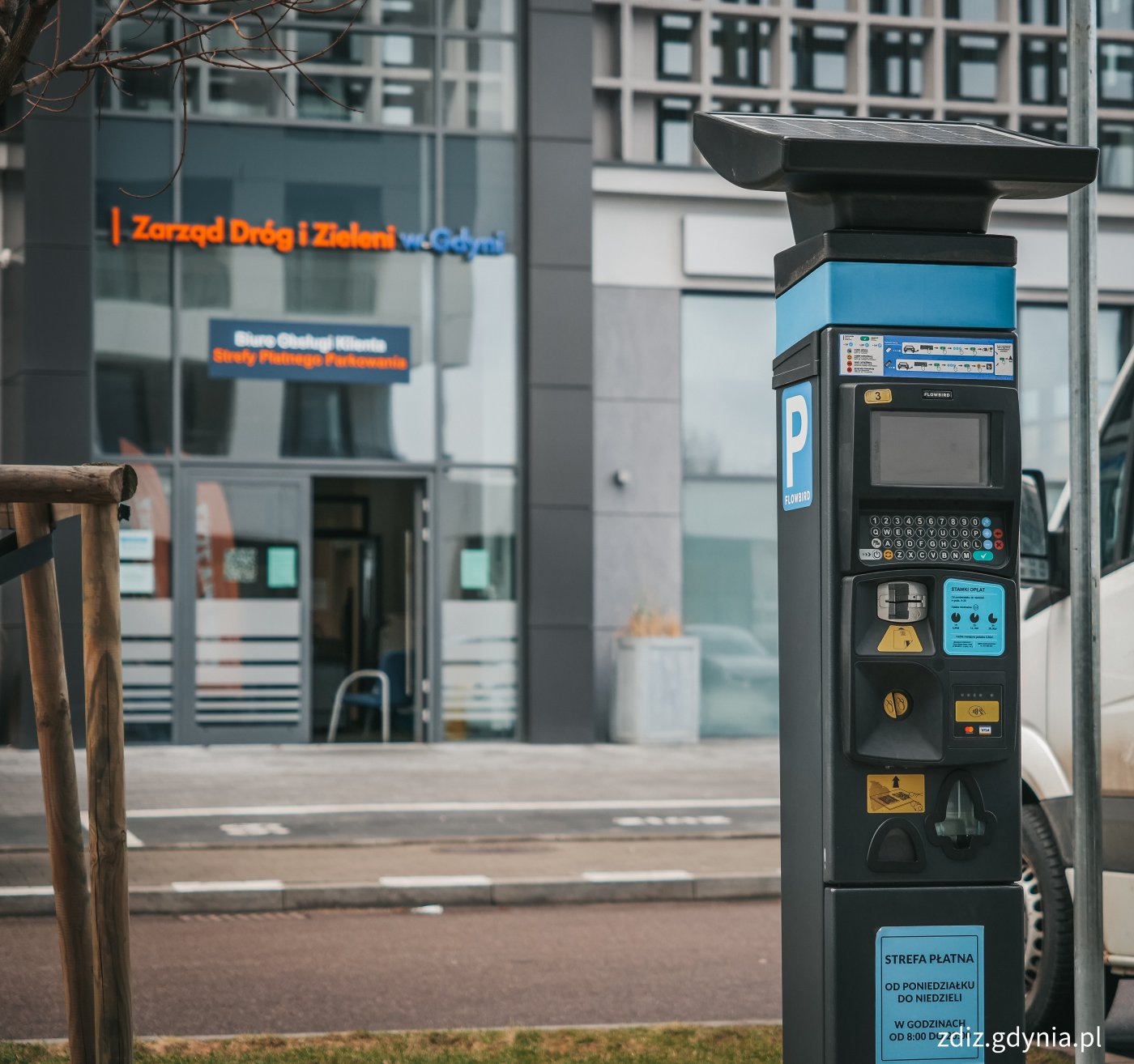 parkomat, w tle budynek w którym mieści się Biuro Obsługi Klienta Strefy Płatnego Parkowania w Zarządzie Dróg i Zieleni w Gdyni