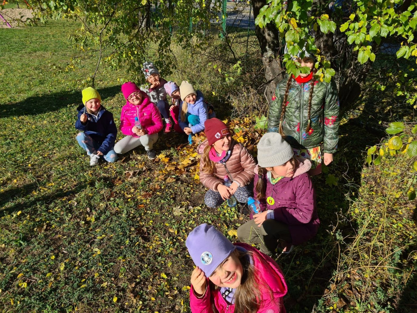 na zdjęciu dzieci usypujące dla jeża kopczyk z liści