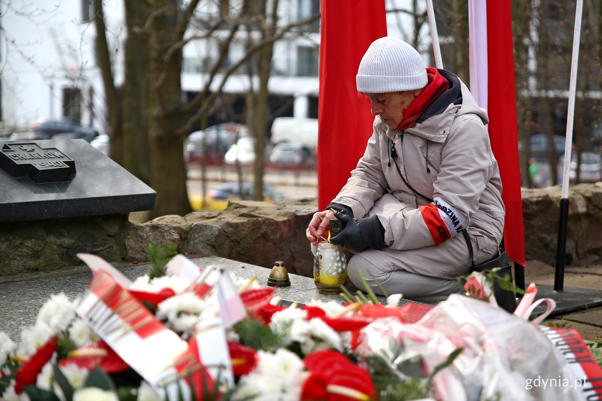 Jedna z uczestniczek uroczystości z okazji Dnia Pamięci Ofiar Zbrodni Katyńskiej zapala znicz na pomniku Ofiar Zbrodni Katyńskiej // fot. Przemysław Kozłowski