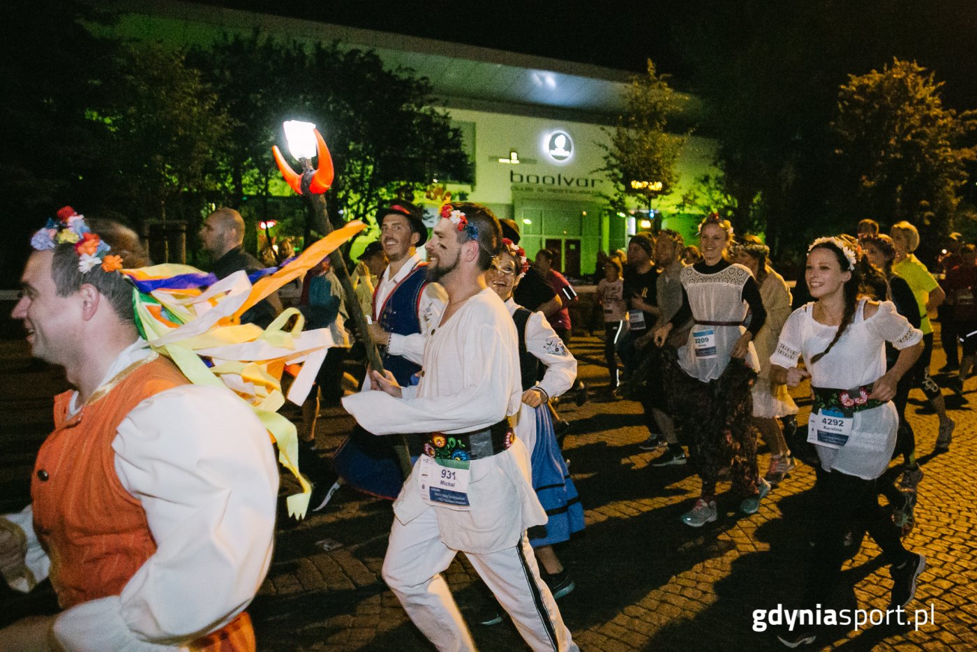 Uśmiechnięci biegacze w ludowych strojach podczas Nocnego Biegu Świętojańskiego w Gdyni