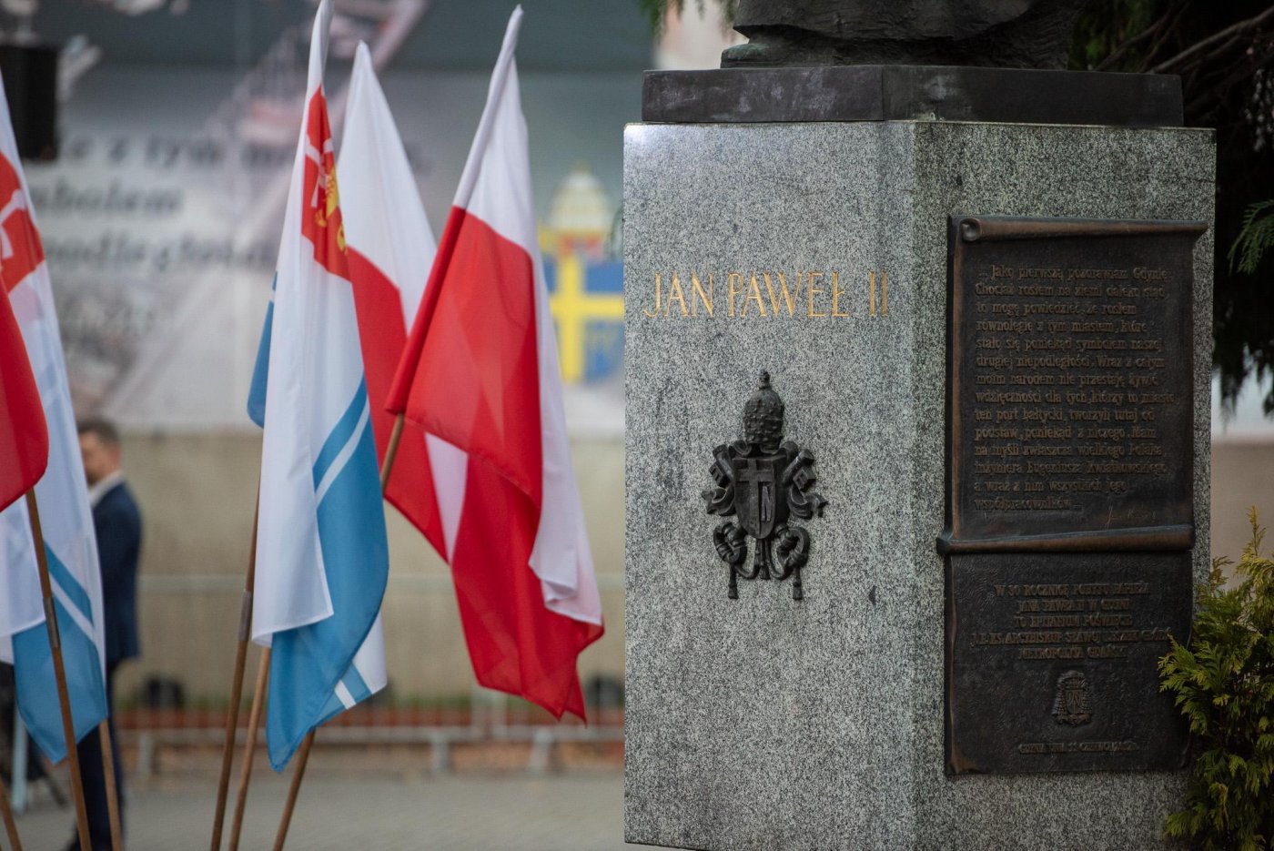 Cokół pomnika Jana Pawła II przy ul. Świętojańskiej, obok stoją flagi Gdyni i maryjne.