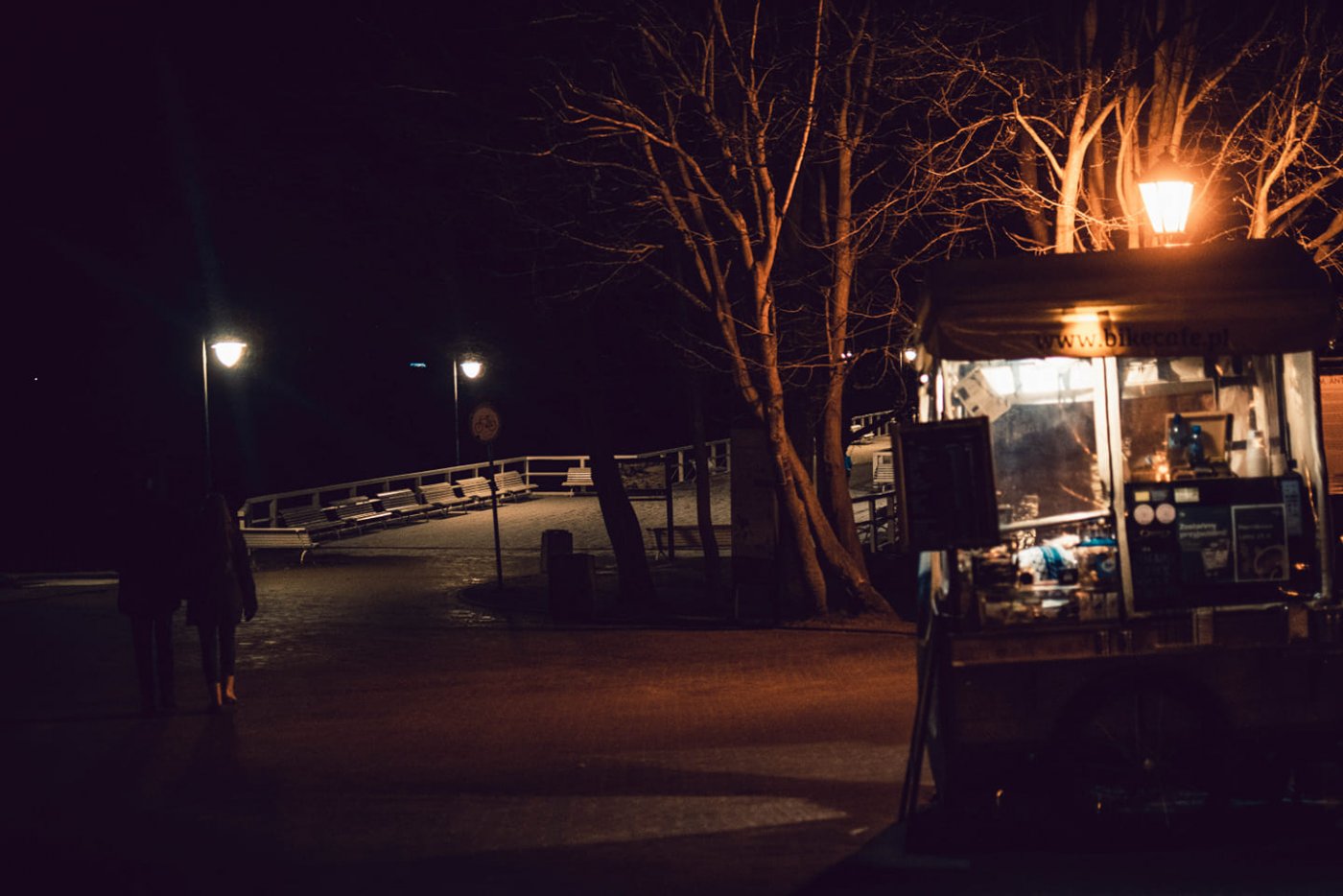 Wieczór, chodnik przy molo w Orłowie. Widoczne latarnie i mobilny punkt gastronomiczny