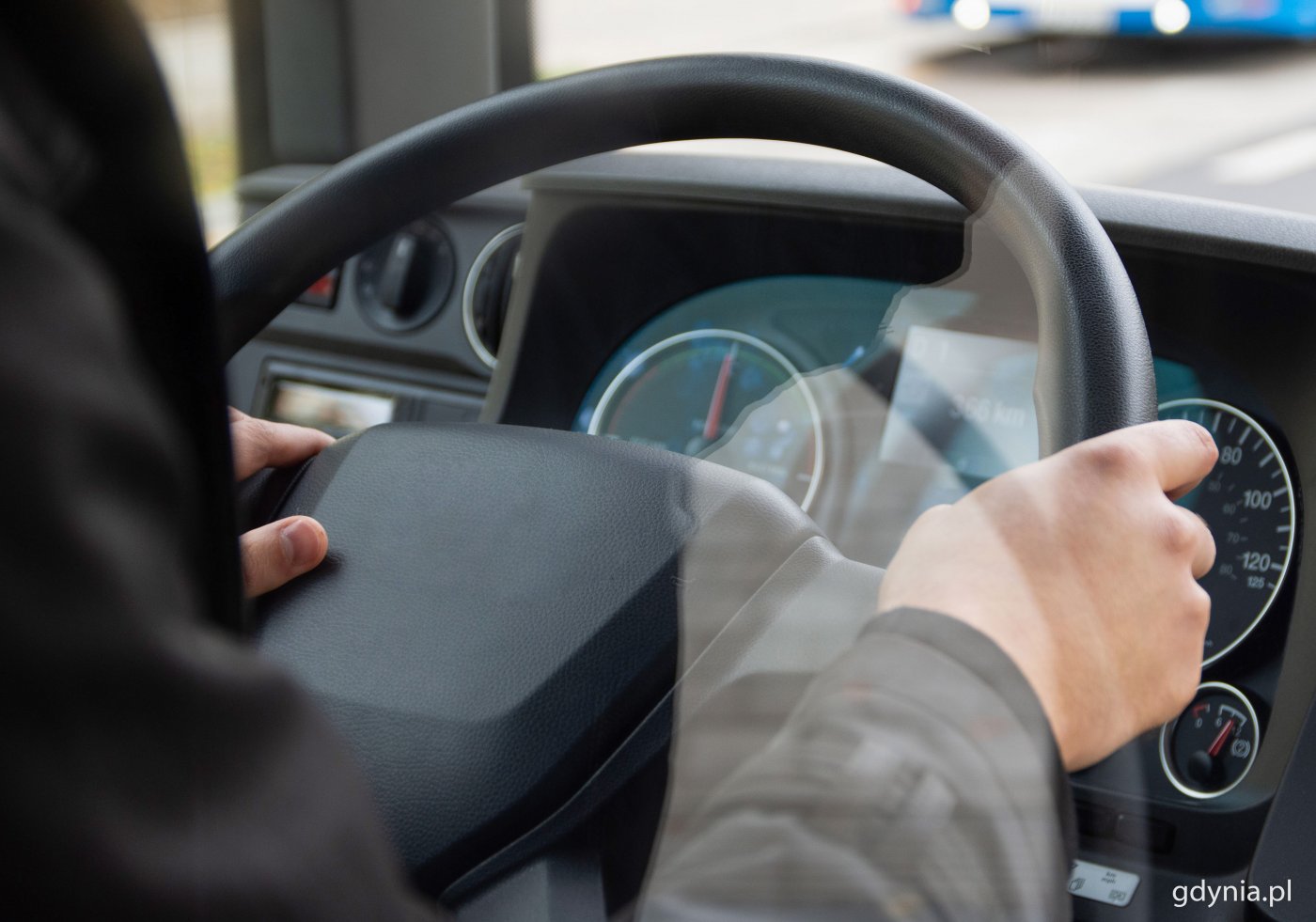 Ręce mężczyzny na kierownicy autobusu, widoczny fragment deski rozdzielczej