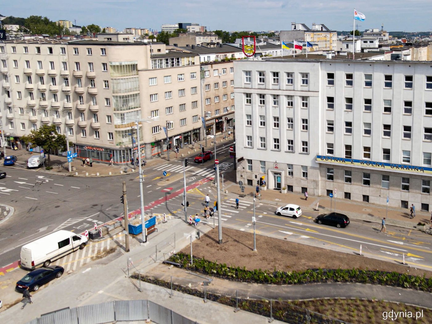 Zdjęcie z drona, skrzyżowanie ulicy Świętojańskiej i alei Piłsudskiego w Gdyni, budynek Urzędu Miasta, fragment budowanego Parku Centralnego, samochody, pieszy, budynki