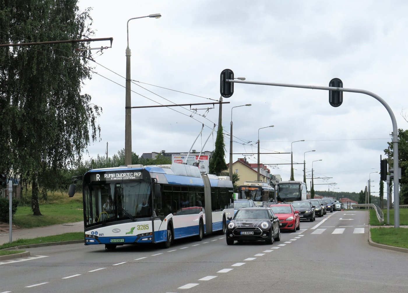 Przegubowy trolejbus Solaris w ruchu ulicznym, podpięty do pantografu. Na wyświetlaczu nazwa linii R, obok samochody.