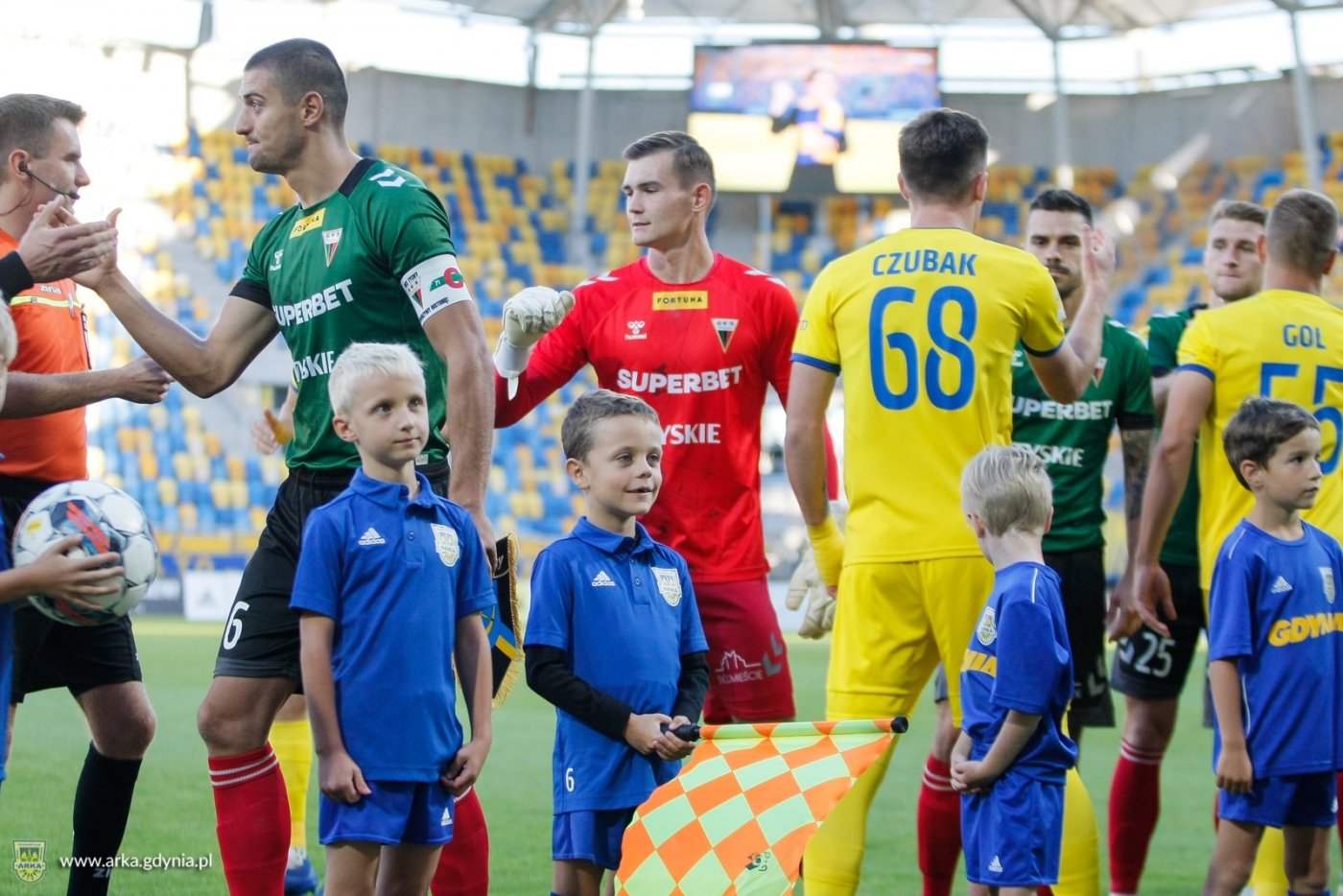 Piłkarze Arki Gdynia i dzieci przed meczem na murawie stadionu miejskiego w Gdyni