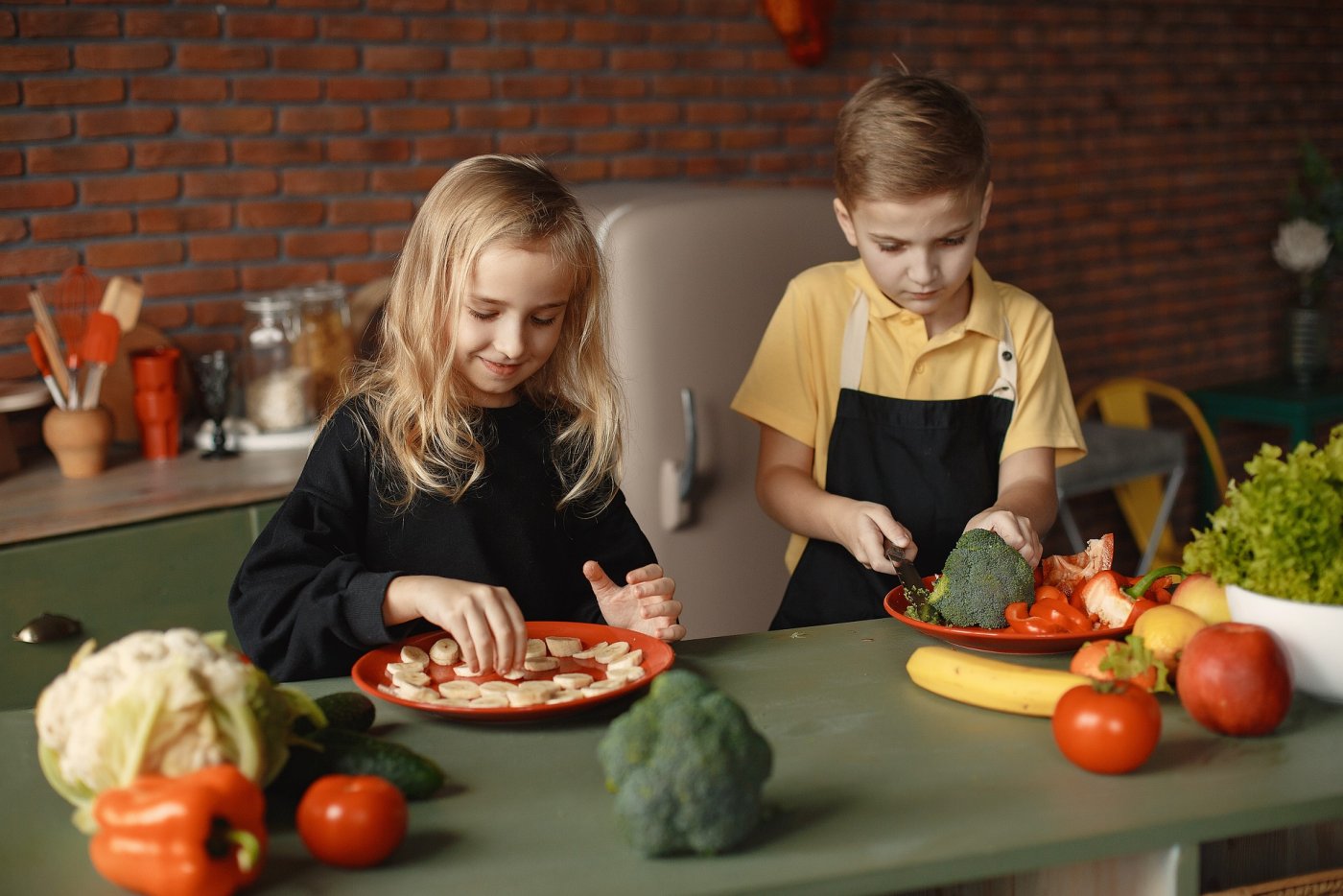 Dziewczynka i chłopiec przygotowują posiłek z kolorowych warzyw.
