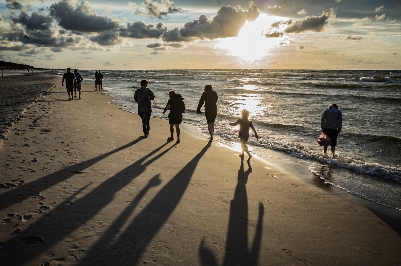 Grupa osób na plaży na tle zachodu Słońca