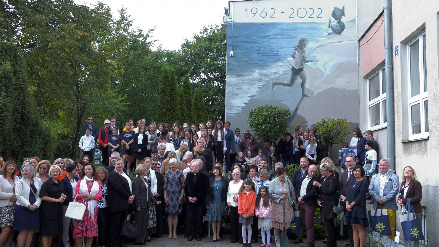 uczestnicy obchodów jubileuszu 60-lecia, przed budynkiem szkoły na tle muralu.