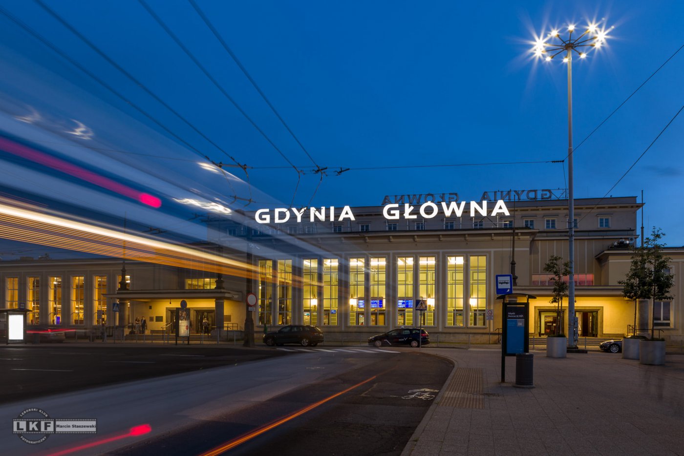 Front budynku dworca kolejowego w Gdyni po zmroku. Podświetlony napis 