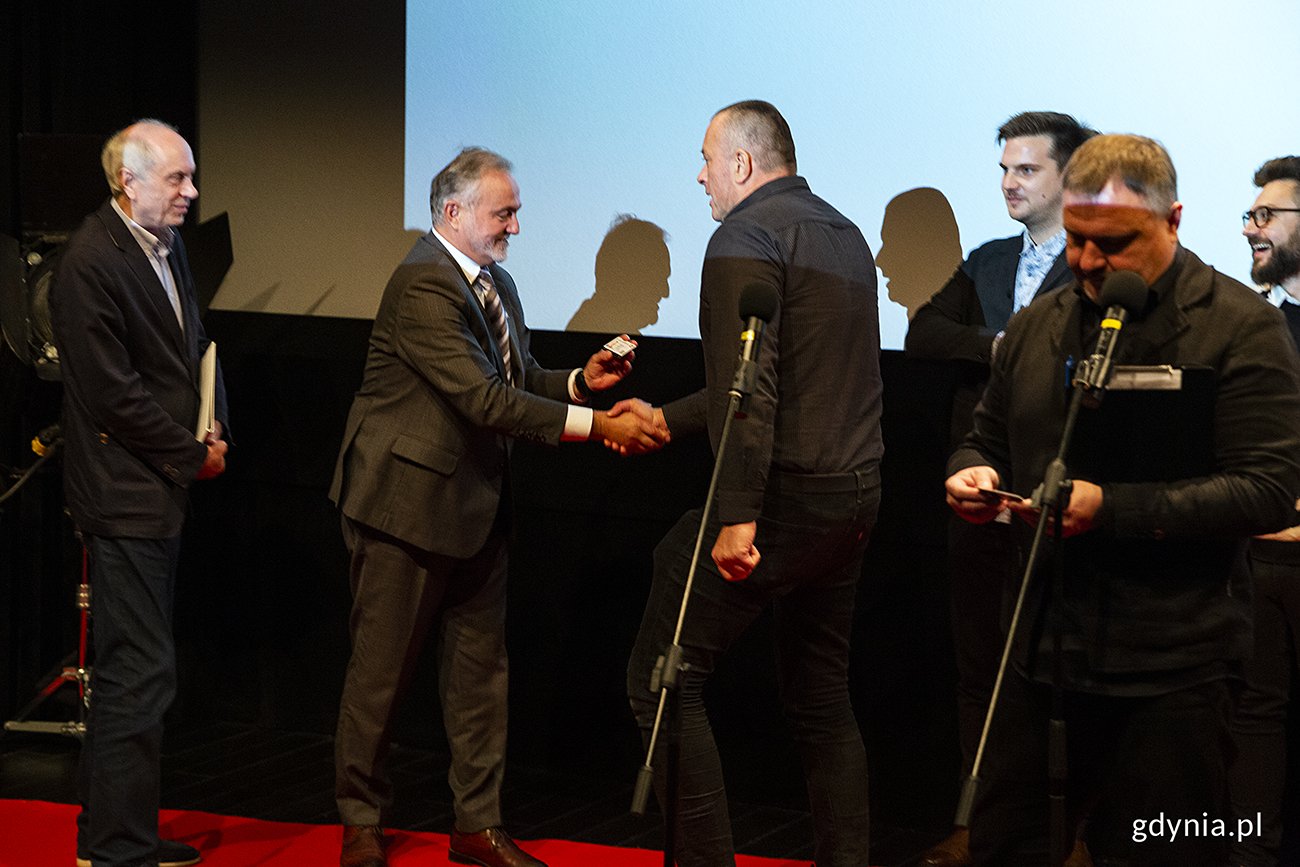 Muzyk Tymon Tymański odbiera z rąk prezydenta Gdyni Wojciecha Szczurka legitymację studenta 1. roku Gdyńskiej Szkoły Filmowej. Fot. Przemysław Kozłowski